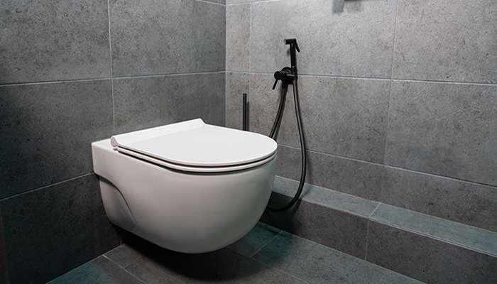 Modern wall mounted toilet or water closet in a tiled bathroom